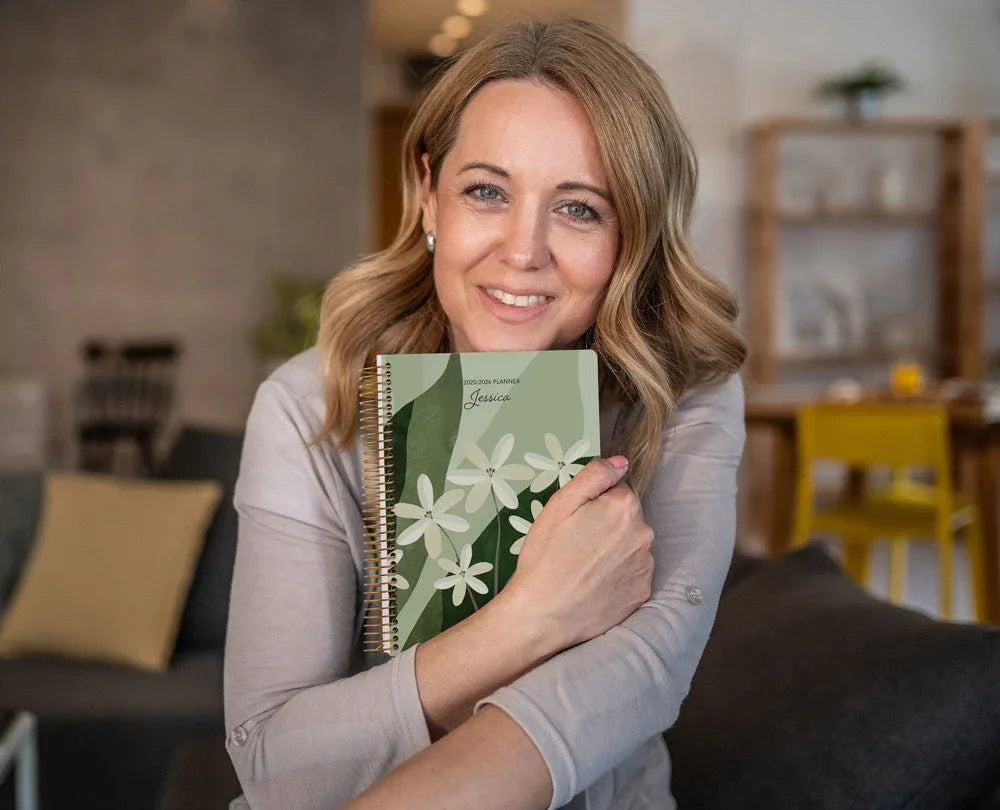 A smiling mid-age woman holding her Posy Paper Co. planner – designed to support her days and celebrate her progress.