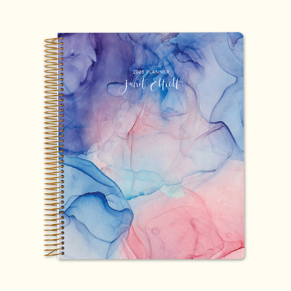 8.5x11 monthly planner with a dreamy pink and purple watercolor flowing ink cover, featuring soft fluid strokes, high-quality paper, and structured monthly pages for seamless planning.