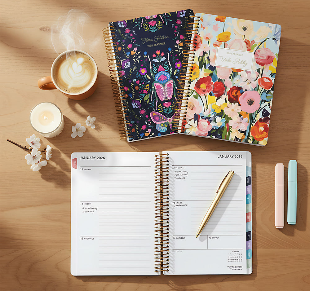 6×9 Posy planner open to a weekly layout with handwritten notes, stacked personalized floral covers above it, gold pen and pastel highlighters on a wooden desk with coffee and candle.