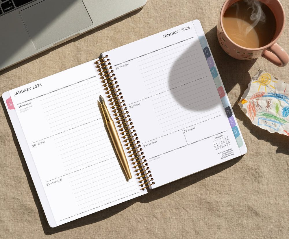 Open Posy Paper Co. weekly planner on a linen desk with a gold pen, laptop, coffee mug, and a child drawing nearby showing a calm workspace that blends personal, work, and family life.