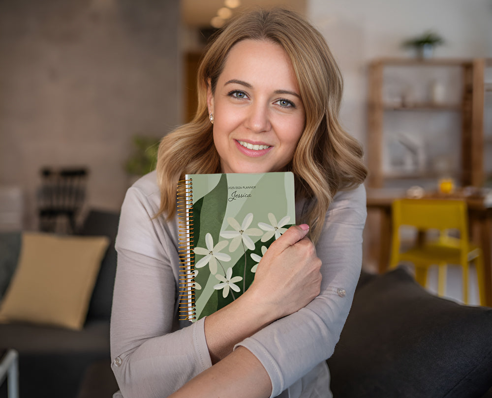 A smiling mid-age woman holding her Posy Paper Co. planner – designed to support her days and celebrate her progress.