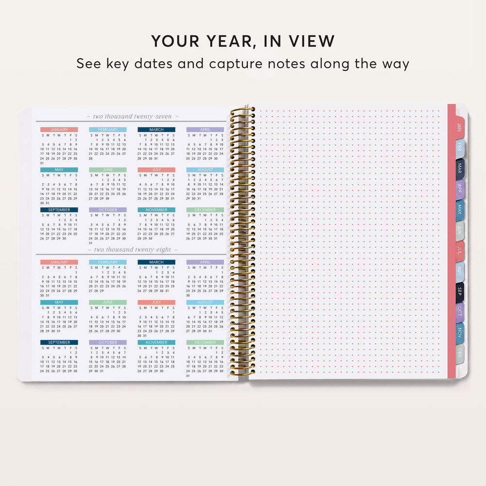 
                  
                    an open spiral-bound notebook with a calendar page inside, showing the months of the year and the days of the week. The notebook has a pink and white color scheme.
                  
                
