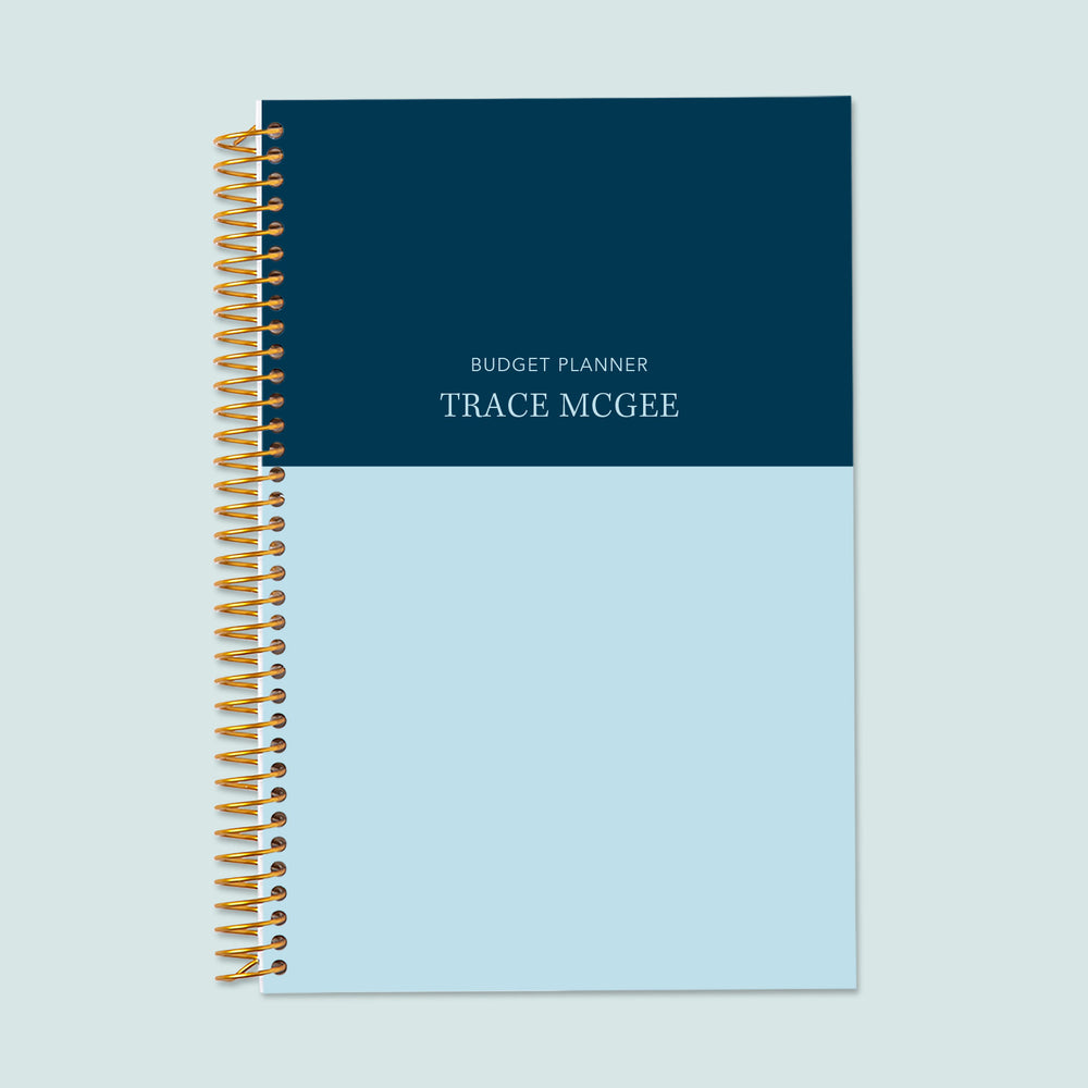 6x9 budget planner with a blue-navy color block cover, a bold, modern aesthetic, organized budgeting sections, and durable coil binding for everyday use.
