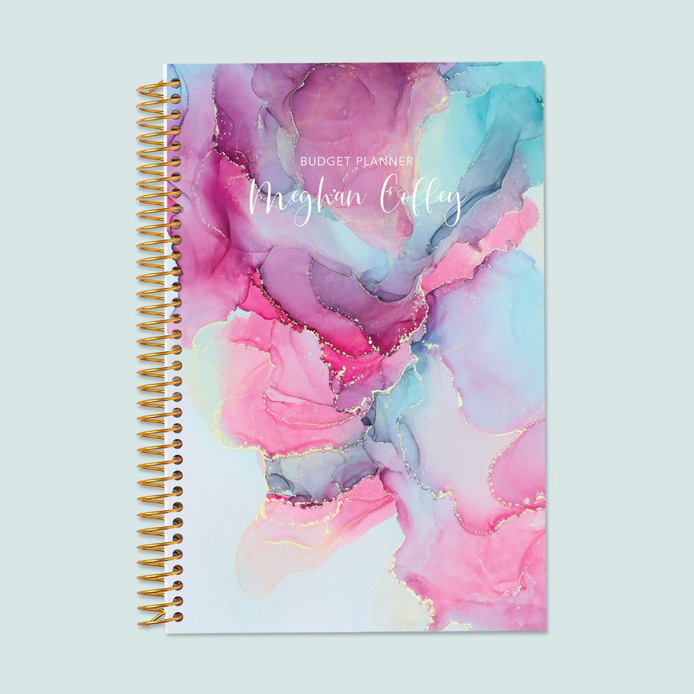 6x9 budget planner with a pink blue abstract ink cover, showcasing fluid abstract artwork, structured finance pages, and goal-setting features for mindful budgeting.
