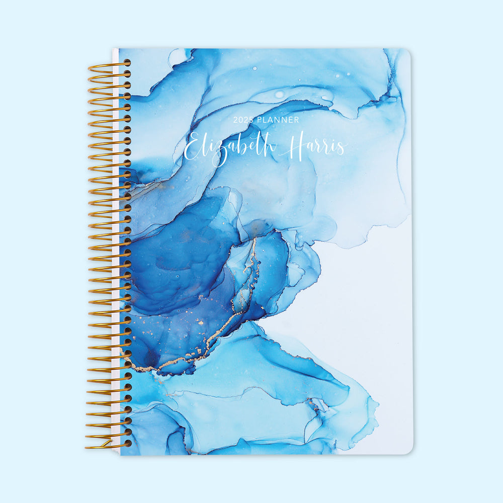 Daily planner with a striking blue abstract ink art cover, featuring an organized daily layout and personalization options to efficiently plan each day.