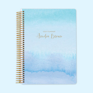 
                  
                    Daily planner with a soothing blue-to-lavender watercolor gradient cover, offering organized daily planning pages and personalized cover details for a tranquil yet efficient planning experience.
                  
                