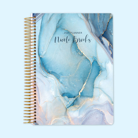 Monthly planner featuring an aqua and gold ink swirl design, mimicking fluid art with a modern metallic touch, bound with a sturdy coil.