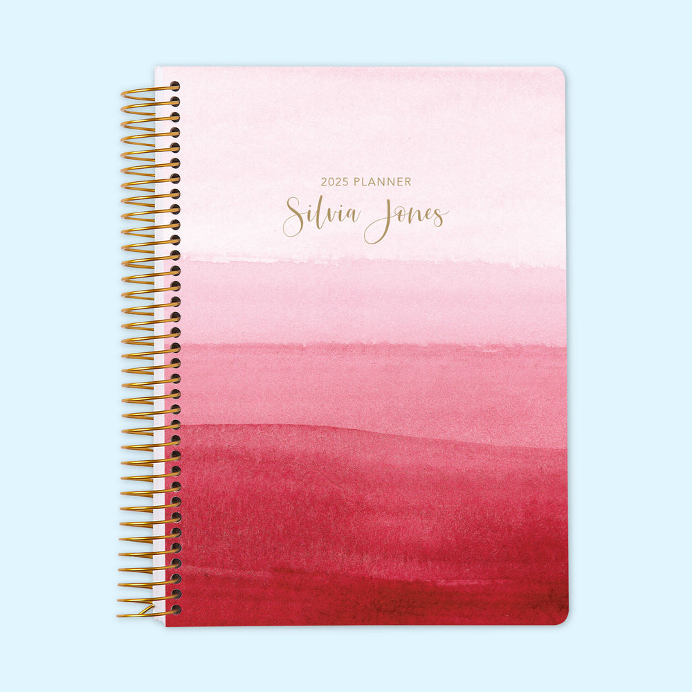 Monthly planner featuring a soft pink ombre watercolor cover, designed for stylish and organized planning. Coil bound for ease of use.