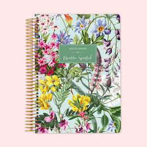 
                  
                    Weekly planner with a vibrant floral cover on a fresh green backdrop, filled with multicolor blossoms, bound by a sturdy spiral and customizable with your name to keep you organized while showcasing your personality.
                  
                