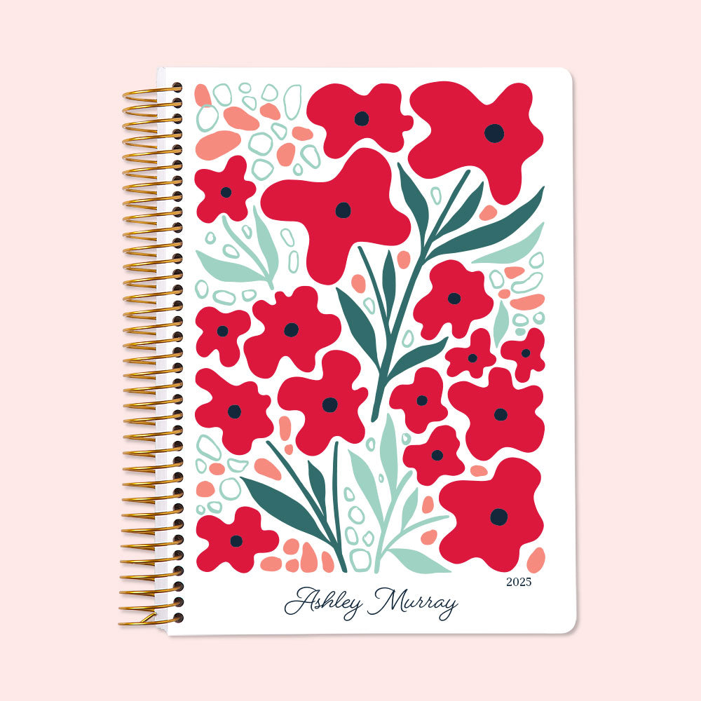 Weekly planner with bold red floral cover art, durable spiral binding, and personalized name, keeping you organized in style.