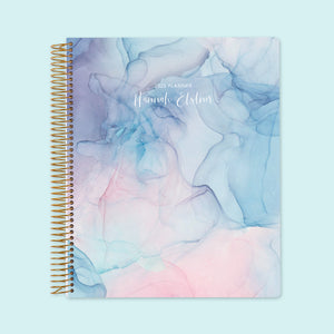 
                  
                    8.5x11 weekly planner with a soft pink and blue flowing ink cover, featuring delicate watercolor swirls, smooth high-quality paper, and spacious weekly planning layouts.
                  
                