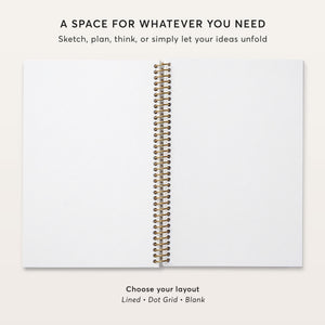 
                  
                    Open notebook showing blank pages and gold coil binding.
                  
                