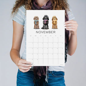 
                  
                    Person holding the November Loyal Companions wall calendar with three dogs
                  
                