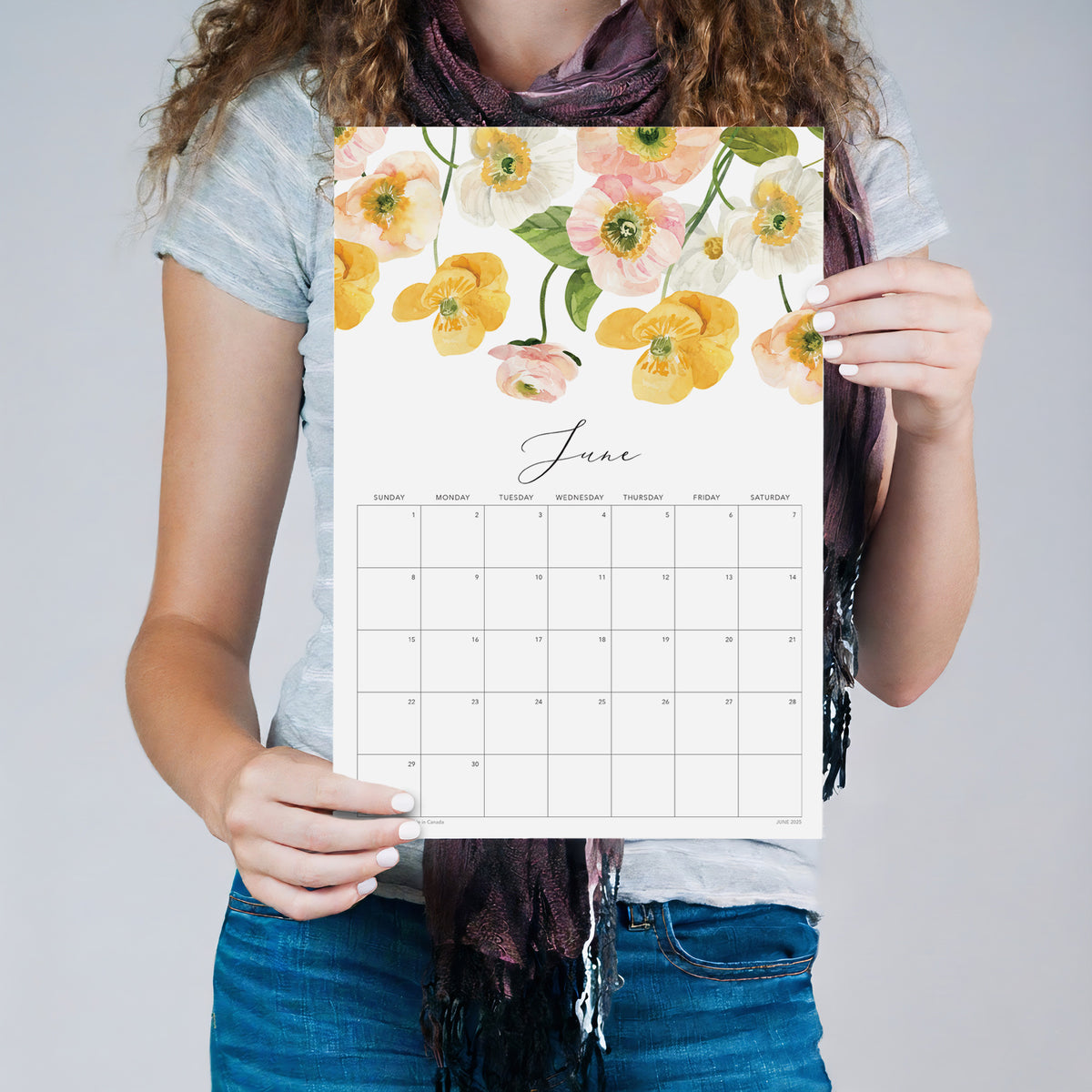 Person holding the June Flirty Florals wall calendar with yellow floral artwork