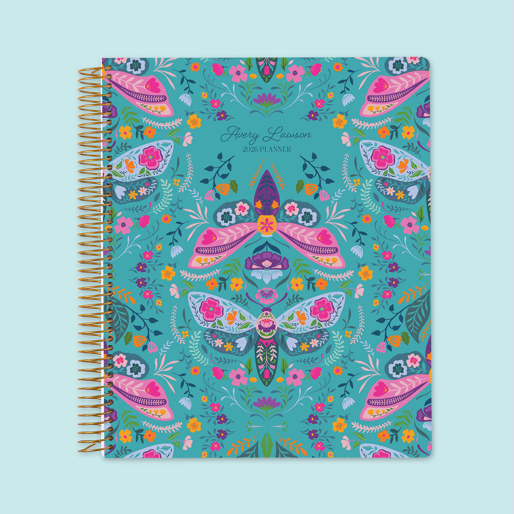 8.5×11 Meadow Daybreak Wings personalized weekly planner with customizable start month, gold coil binding, and a whimsical teal floral cover featuring illustrated moths, butterflies, and garden accents.