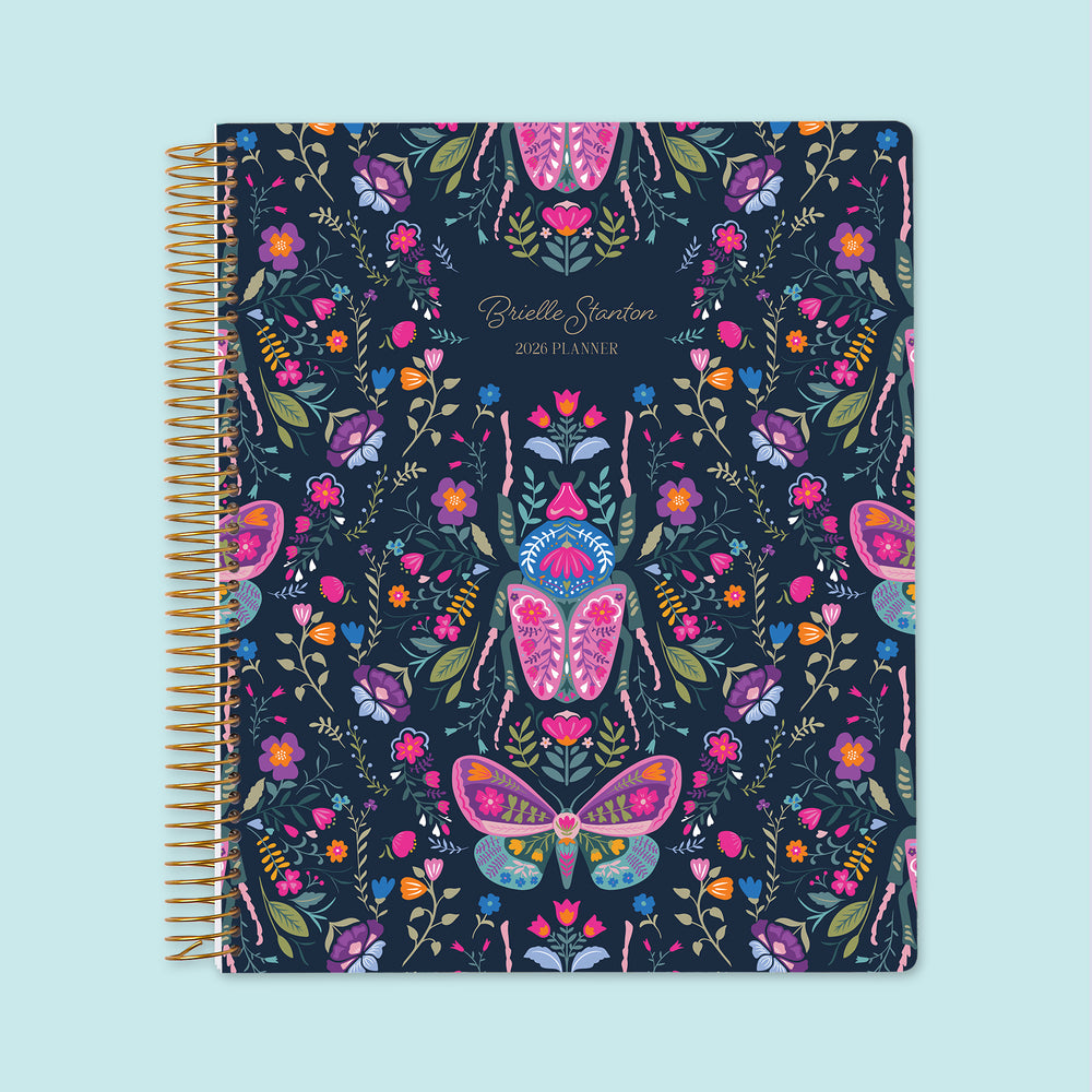8.5×11 Midnight Garden Wings personalized weekly planner with customizable start month, gold coil binding, and a deep navy floral cover featuring illustrated butterflies, moths, and vibrant garden botanicals.