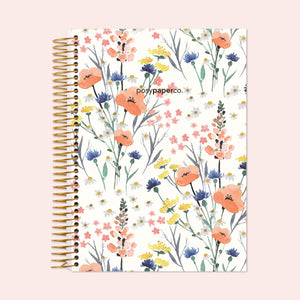 
                  
                    6×9 hardcover monthly planner with a Field Flowers Blue cover and gold coil binding.
                  
                