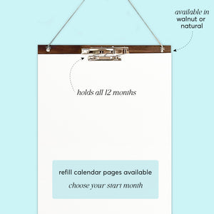 
                  
                    Back of a wall calendar showing the wooden hanger, clips and cord.
                  
                