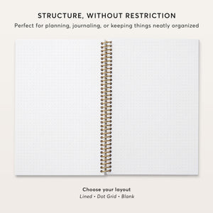 
                  
                    Open notebook showing dot-grid pages and gold coil binding.
                  
                