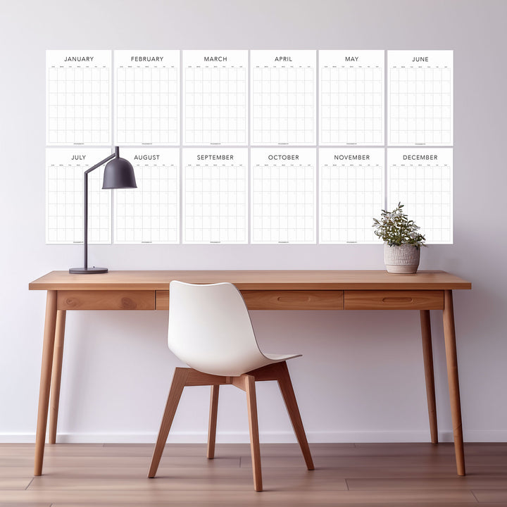 White undated wall calendar with all twelve months displayed above a desk