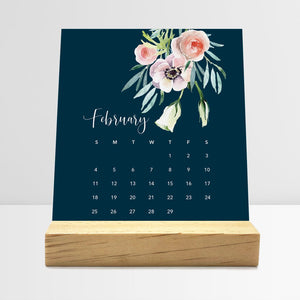 
                  
                    February Floral desk calendar card with watercolor flowers in a wooden stand.
                  
                